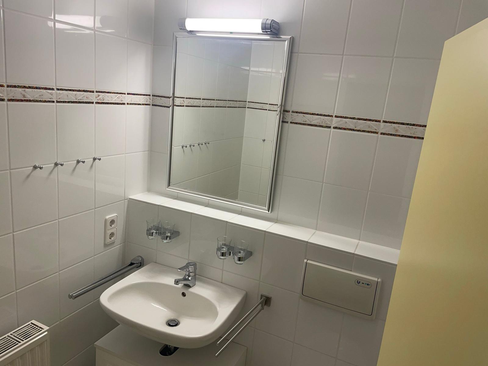 Badezimmer mit Waschbecken, Spiegel und Handtuchhalter.
