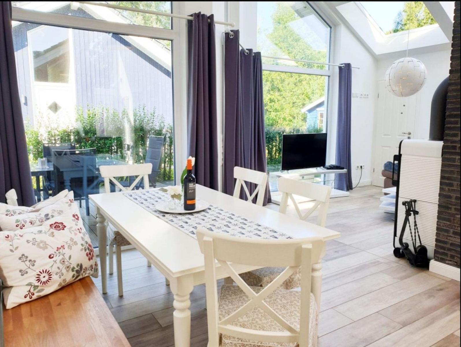 Essbereich mit weißem Tisch und Stühlen, großes Fenster und Blick auf Garten.