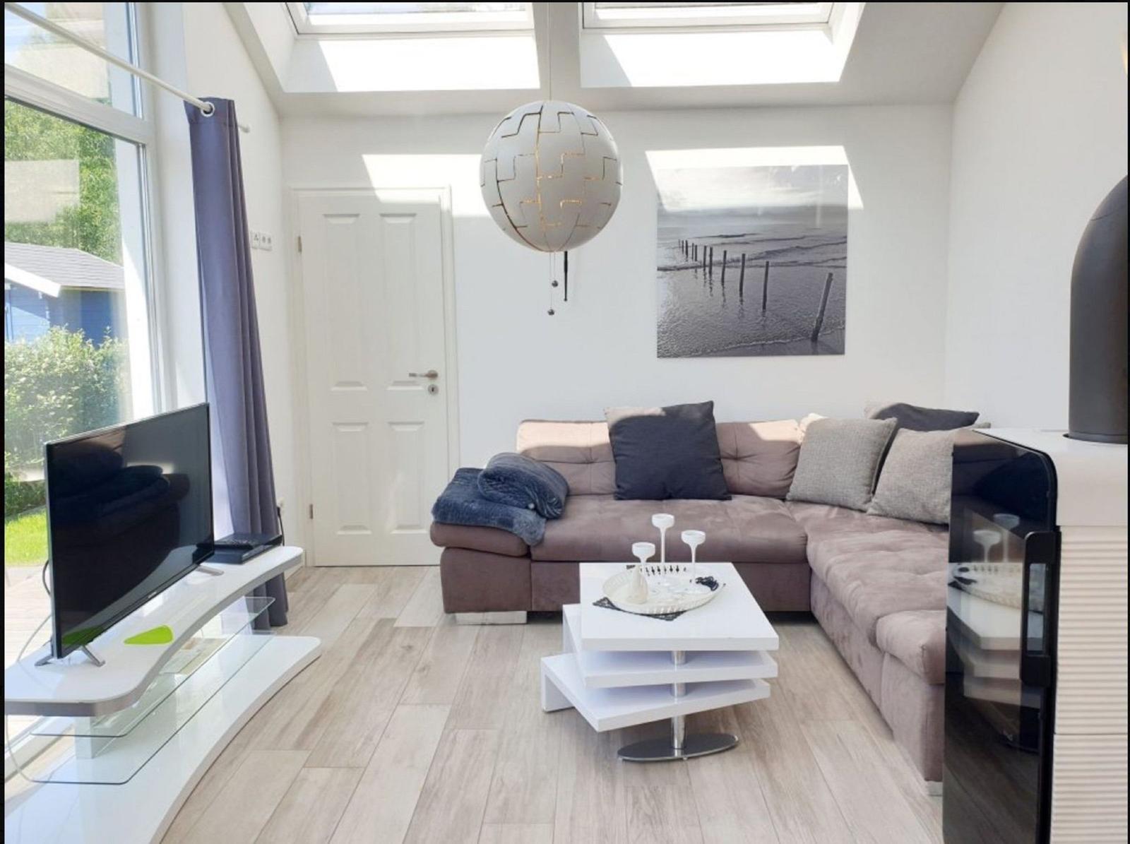 Wohnzimmer mit Sofa, Fernseher und Deckenfenstern.