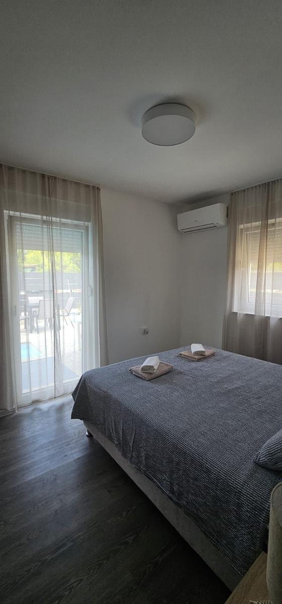 Schlafzimmer mit Bett, Klimaanlage und Blick auf Poolbereich.