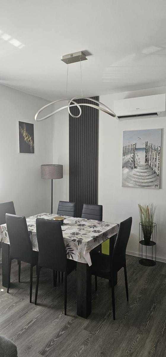 Esszimmer mit Tisch, Stühlen und moderner Deckenleuchte.