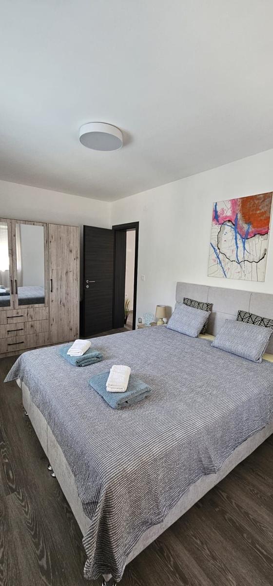 Schlafzimmer mit Bett, Kleiderschrank und Wandbild.
