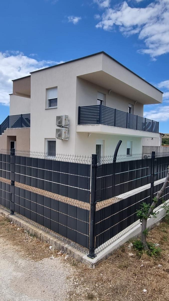 Moderne zweistöckige Villa mit Balkon und schwarzer Umzäunung.