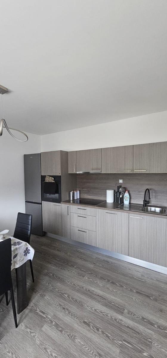 Moderne Küche mit Küchenzeile, Spüle und Kühlschrank. Essbereich mit Tisch und Stühlen.