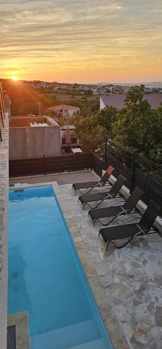 Poolbereich mit Liegestühlen und Blick auf Sonnenuntergang