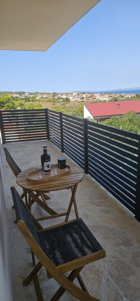 Terrasse mit Tisch und Stühlen, Blick auf Landschaft und Meer.