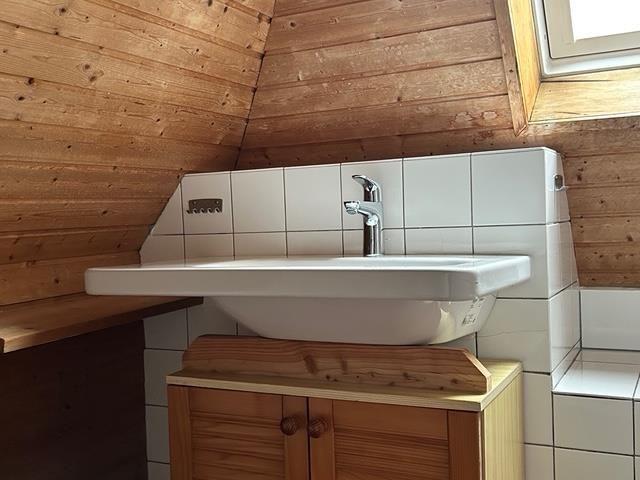 Waschbecken mit Holzunterschrank und Fliesenwand in Dachschrägen