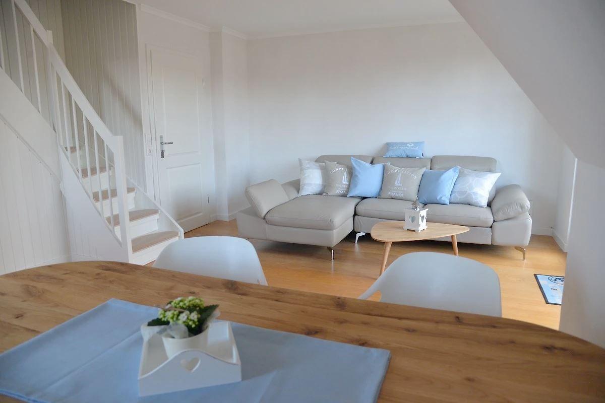Wohn- und Essbereich mit Sofa, Tisch und Stühlen. Hintergrund: Treppe und Tür.