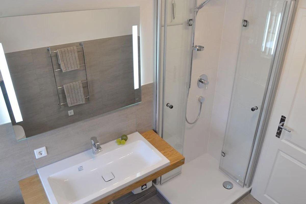 Badezimmer mit Dusche, Waschbecken und Spiegel
