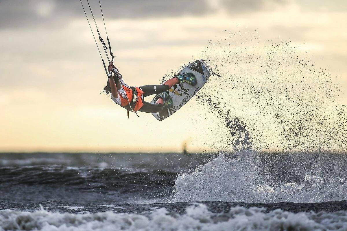 Kitesurfer vollführt eine Sprungaktion über das Meer bei Sonnenuntergang.