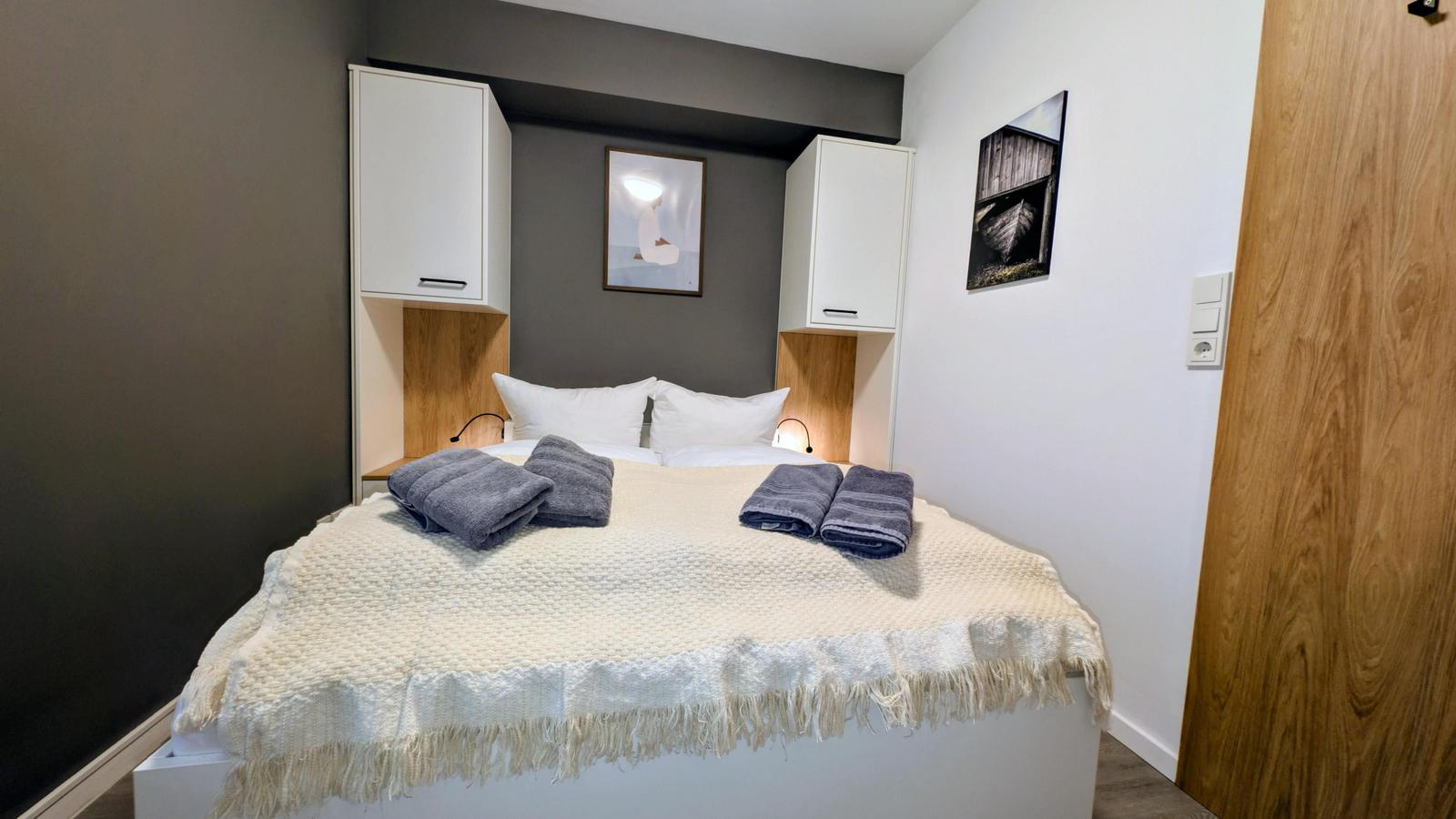 Schlafzimmer mit Bett, weißen Kabinen und Kunst an der Wand.