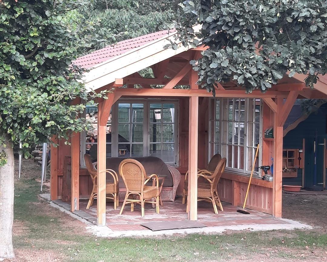 Wooden covered area with chairs and windows under trees