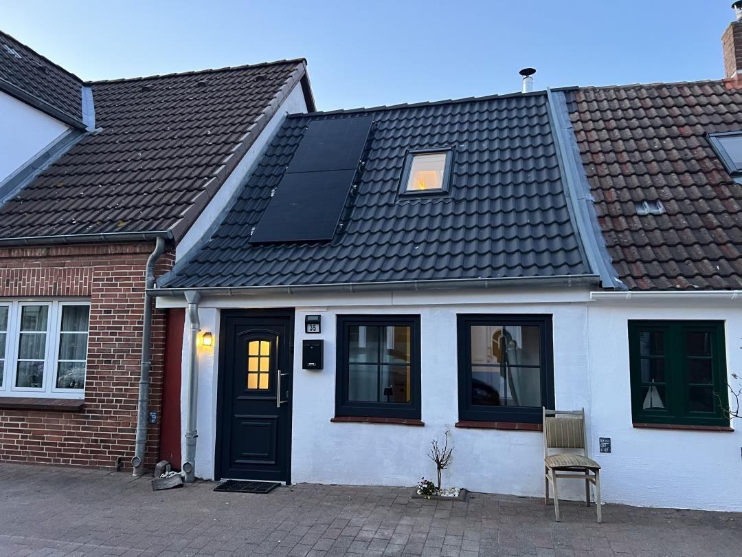 House with white facade, dark windows, and solar panels on roof
