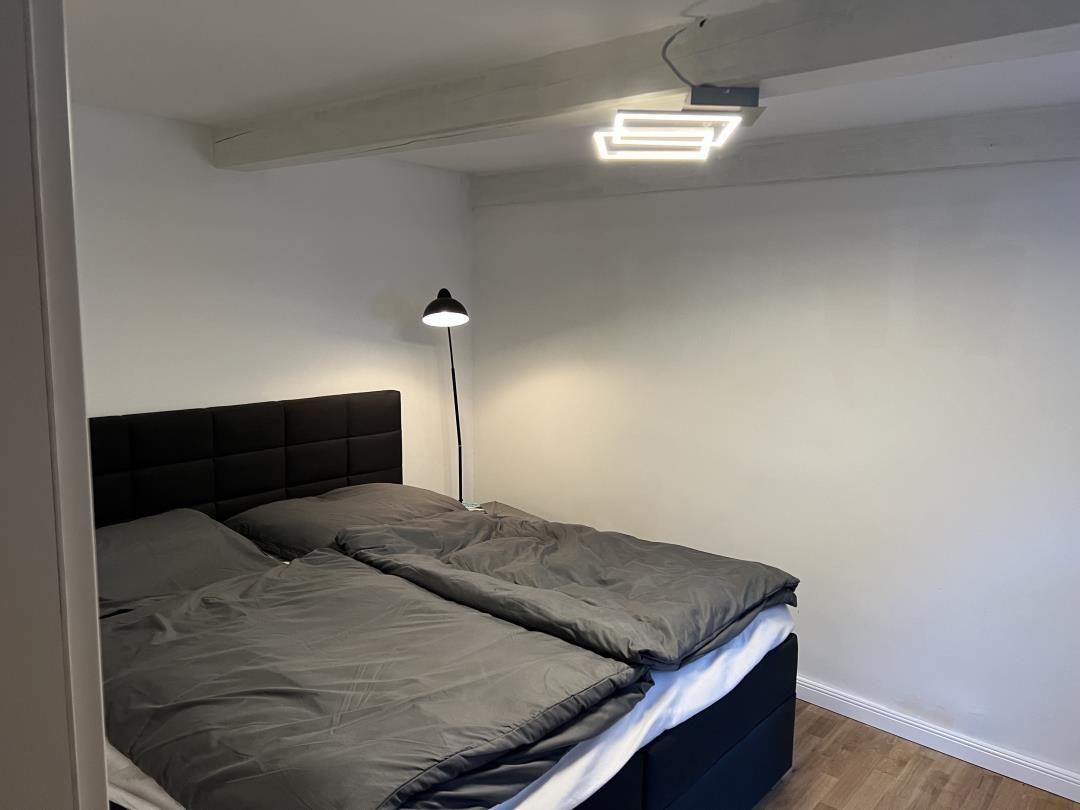 Bedroom with double bed, black headboard, and floor lamp.