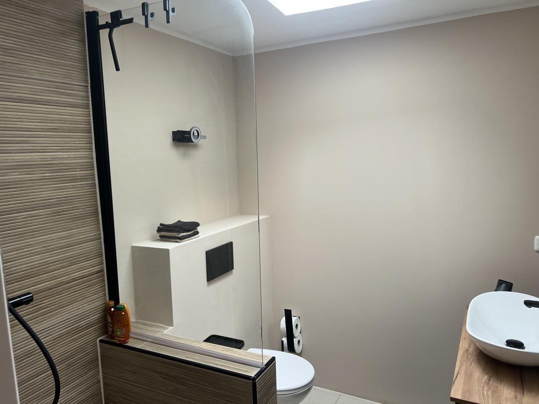 Bathroom with shower, toilet, and sink on wooden countertop.