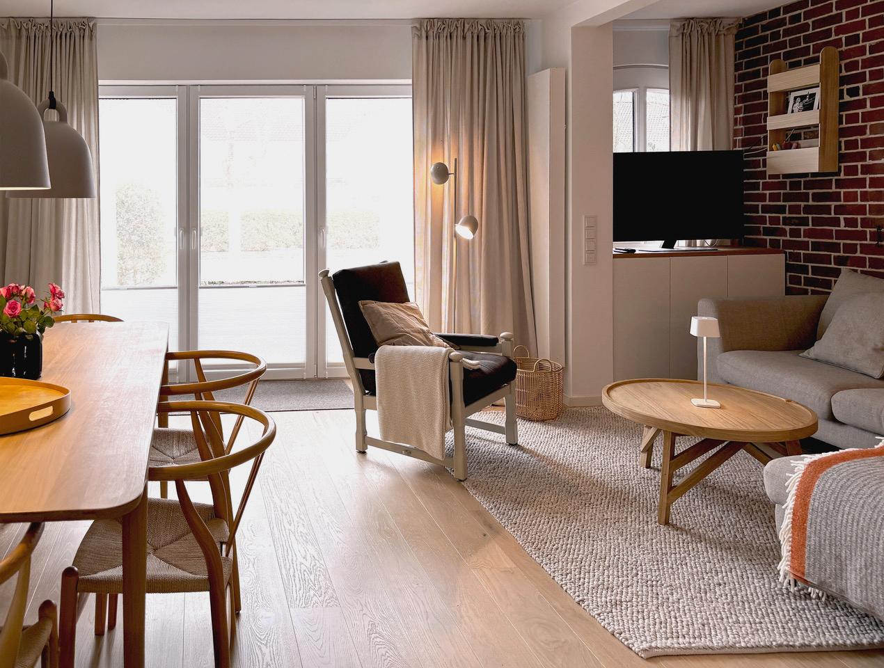 Wohn- und Essbereich mit Holzboden, Sofa, Sessel und Esszimmertisch.