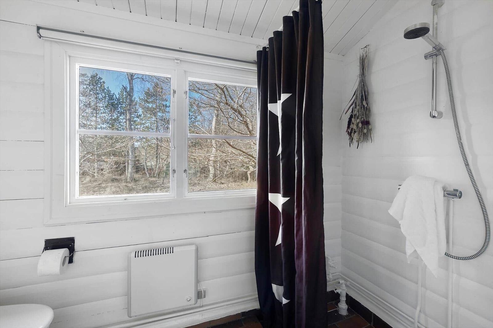 Bathroom with shower, window, and dark curtain with star pattern.