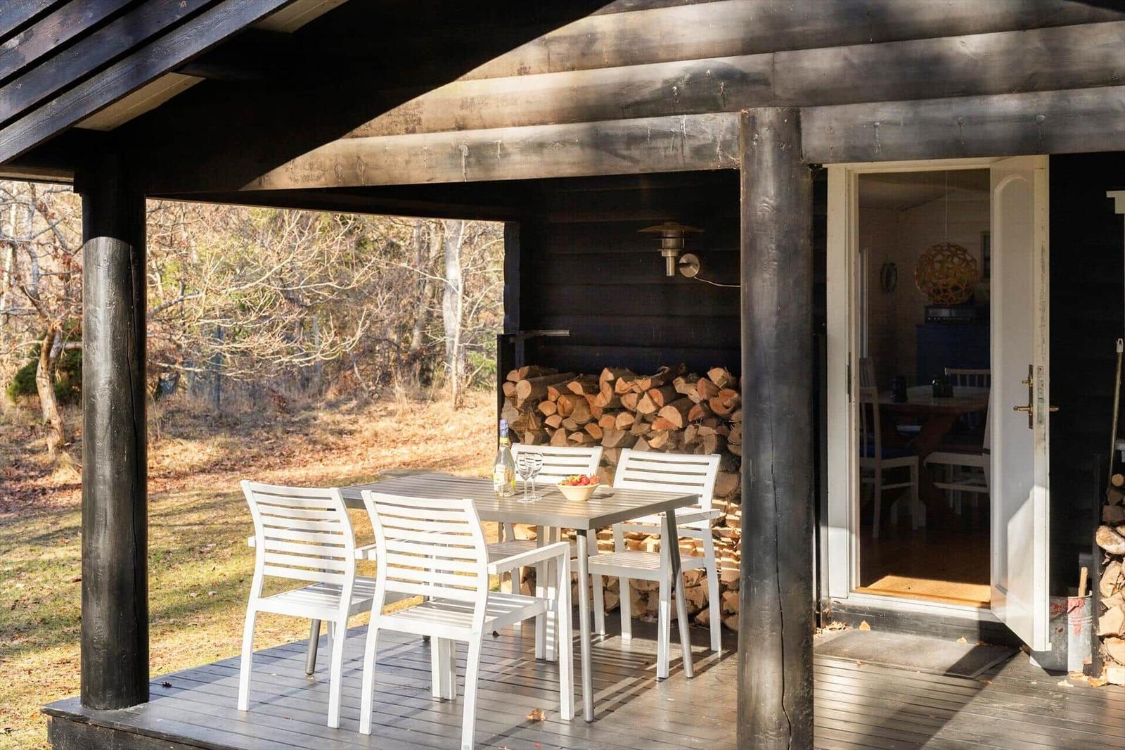 Patio with table and chairs, woodpile, and view into the house.