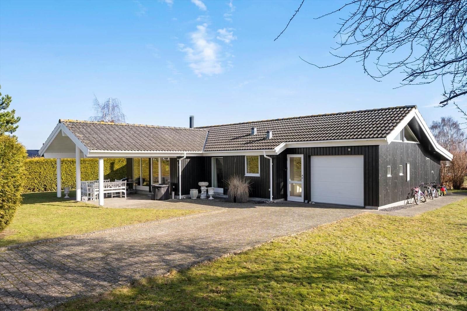 A house with garage, terrace and garden under blue sky.