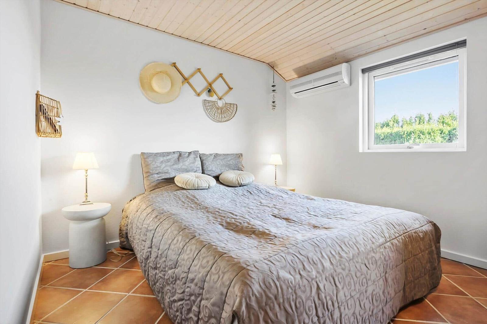 Bedroom with bed, window, and wooden ceiling.