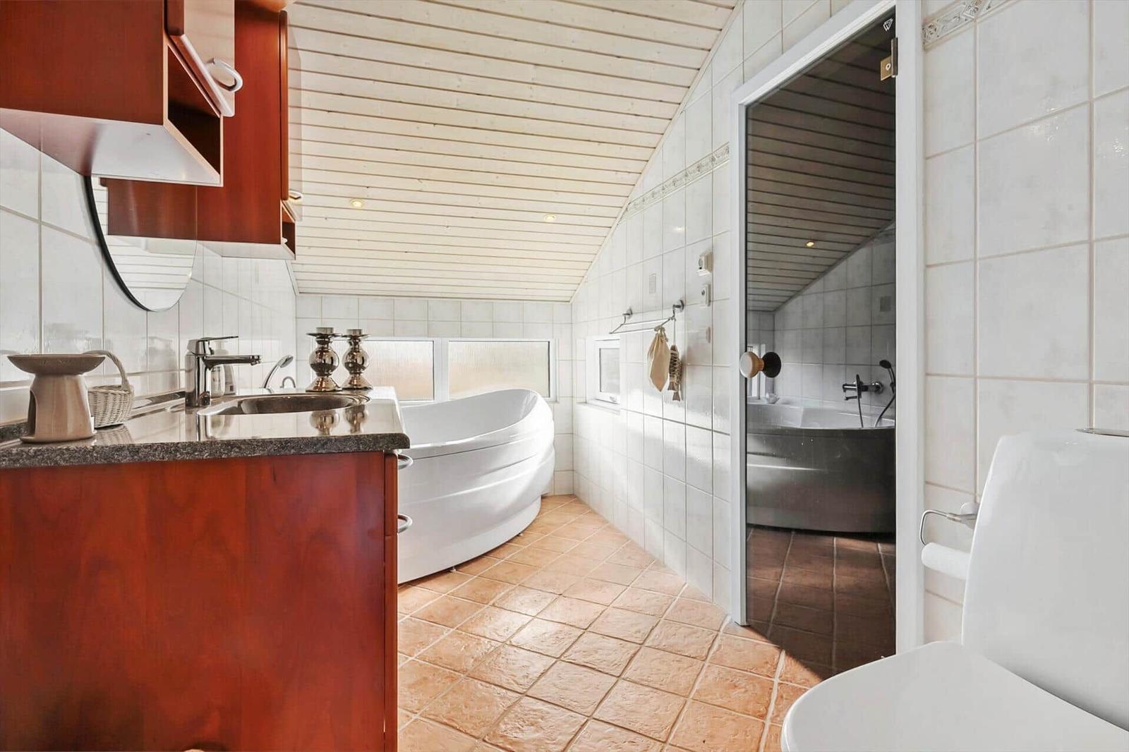 Bathroom with bathtub, sink and toilet. Passage to shower with bathtub.