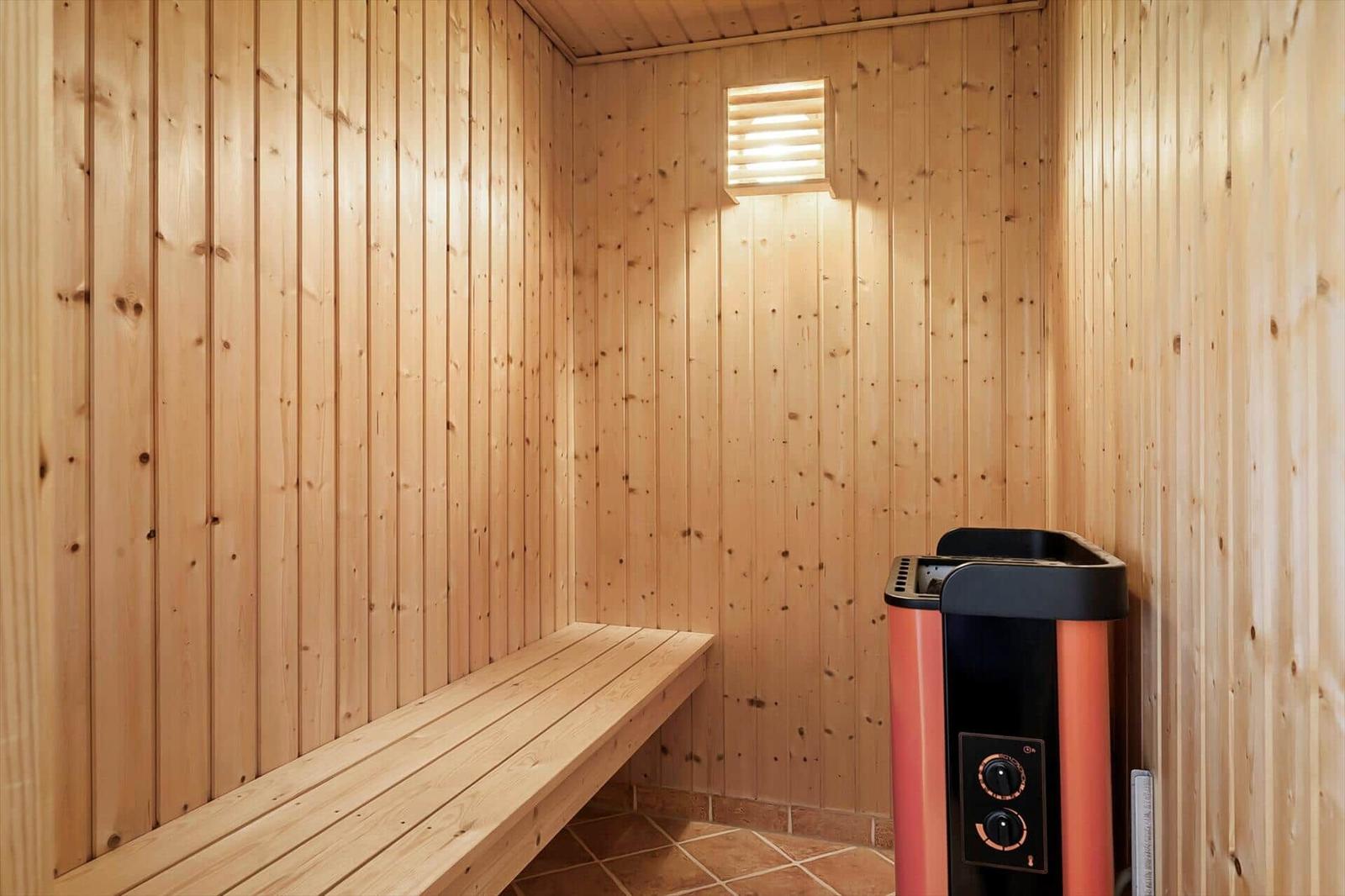 Sauna with wooden walls, bench, and heater.