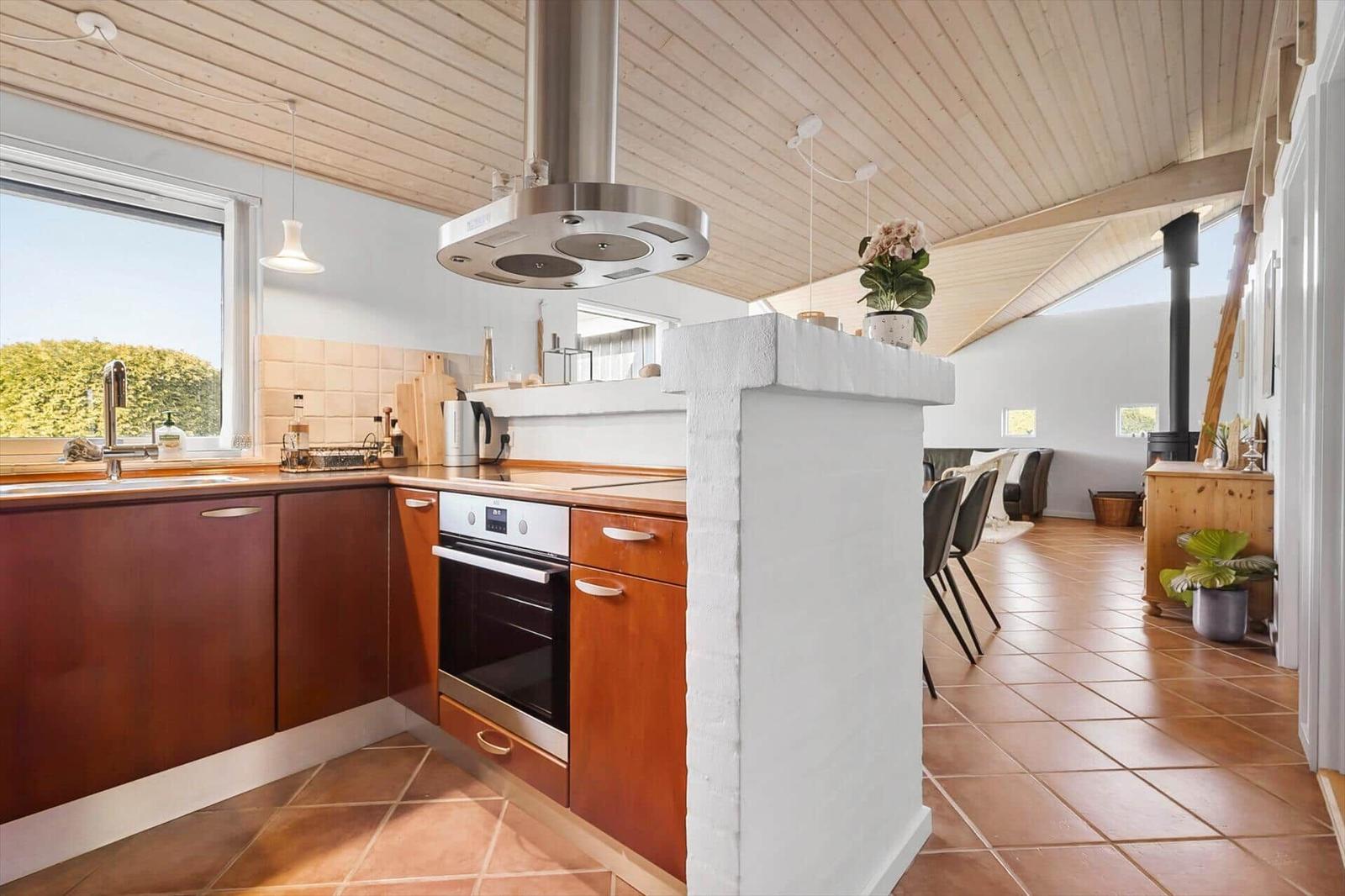Kitchen with wooden ceiling, stainless steel stove, and terracotta floor