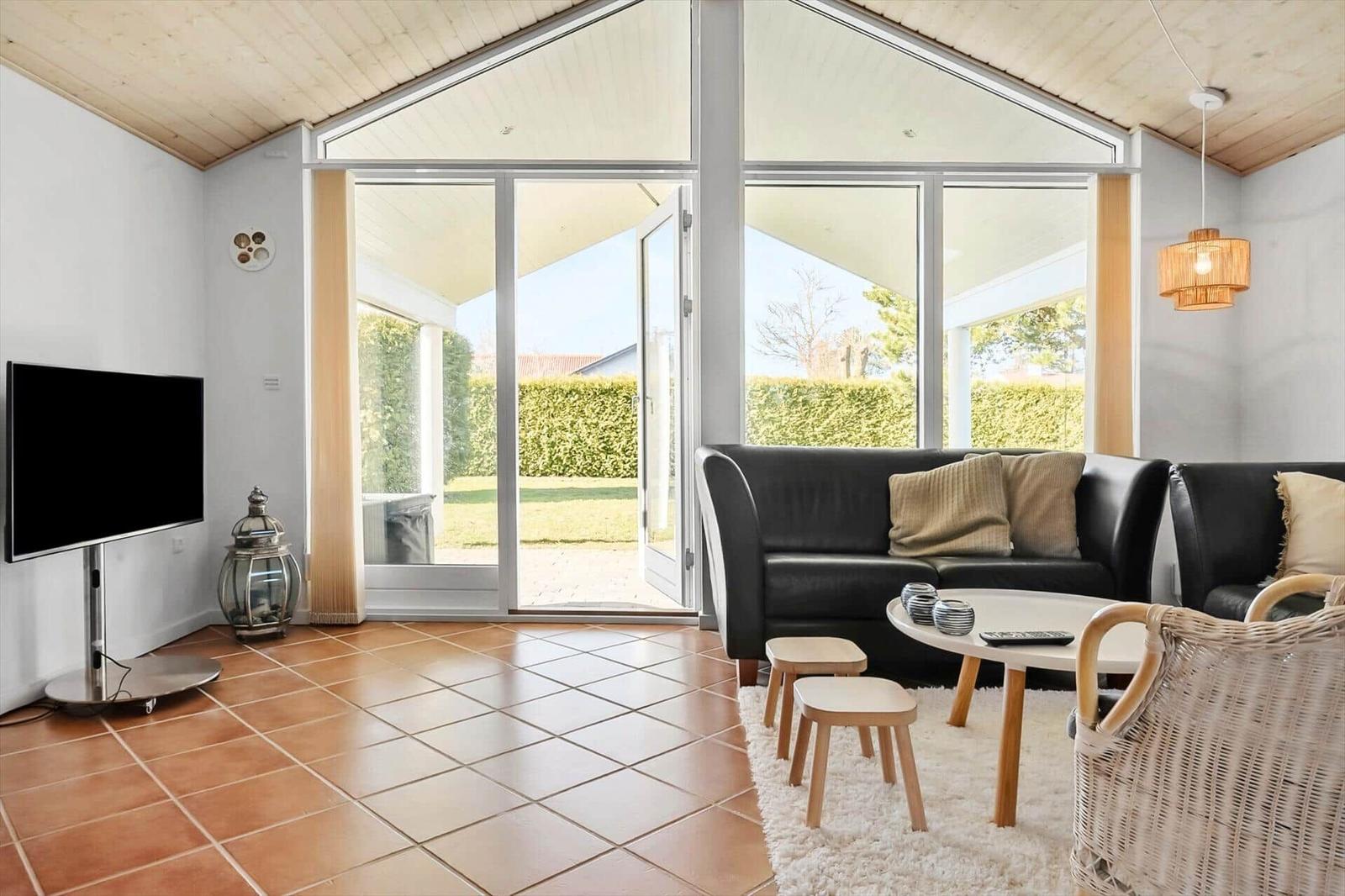 Living room with sofa, TV, and view of garden