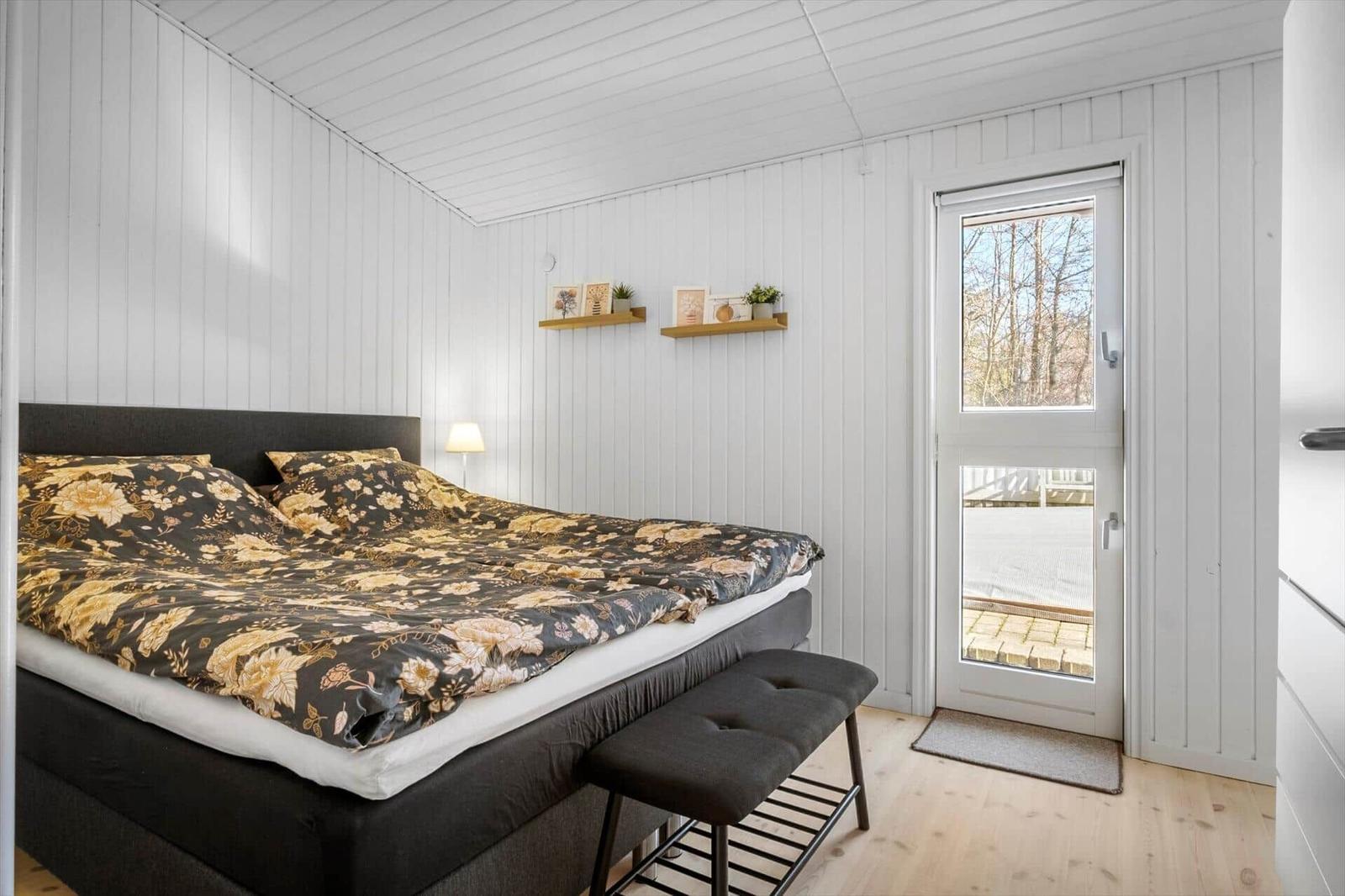 Bedroom with bed, window and wooden floor.