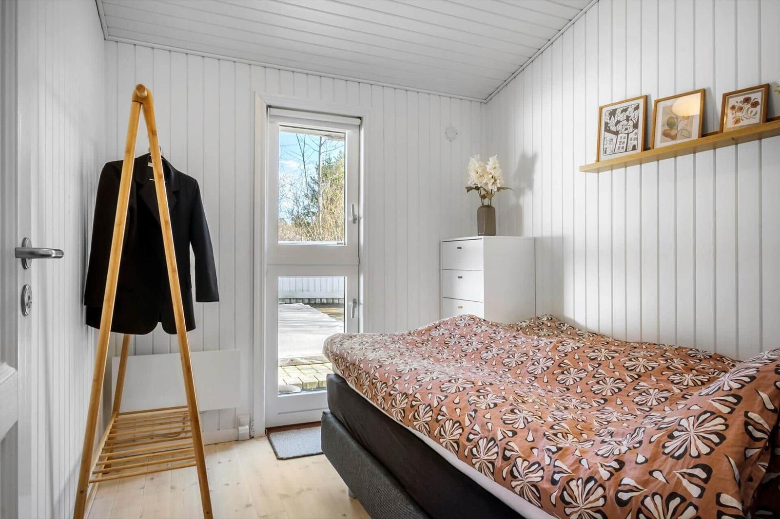 Bedroom with bed, coat stand, and window to balcony.