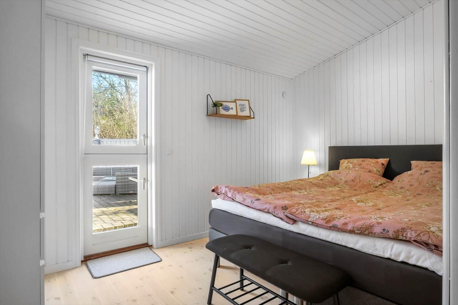 Bedroom with bed, door to balcony, and wall shelf.