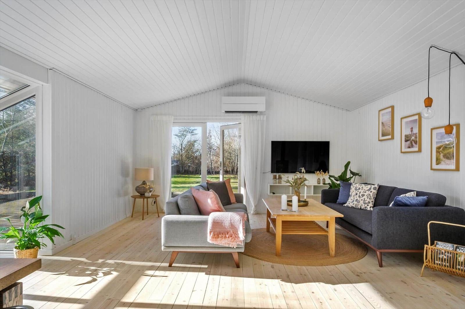 Living room with sofa, couch and TV. Wooden floor and white walls.