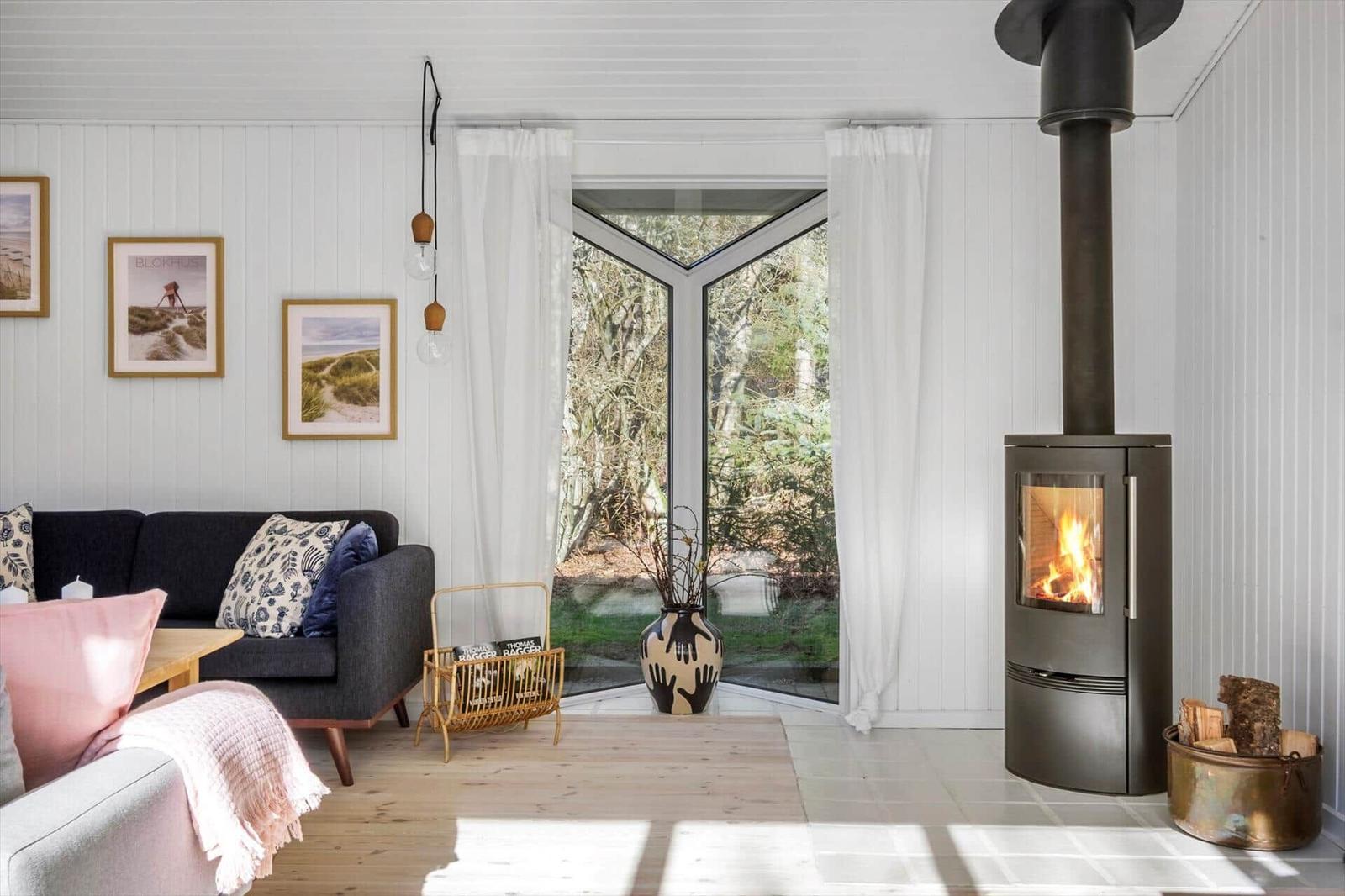 Living room with fireplace, sofa, and garden view through window.