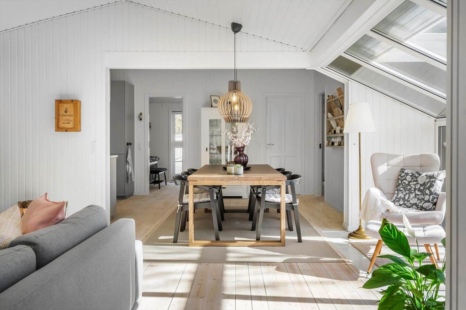 Living and dining area with wooden table, seating, and skylights.