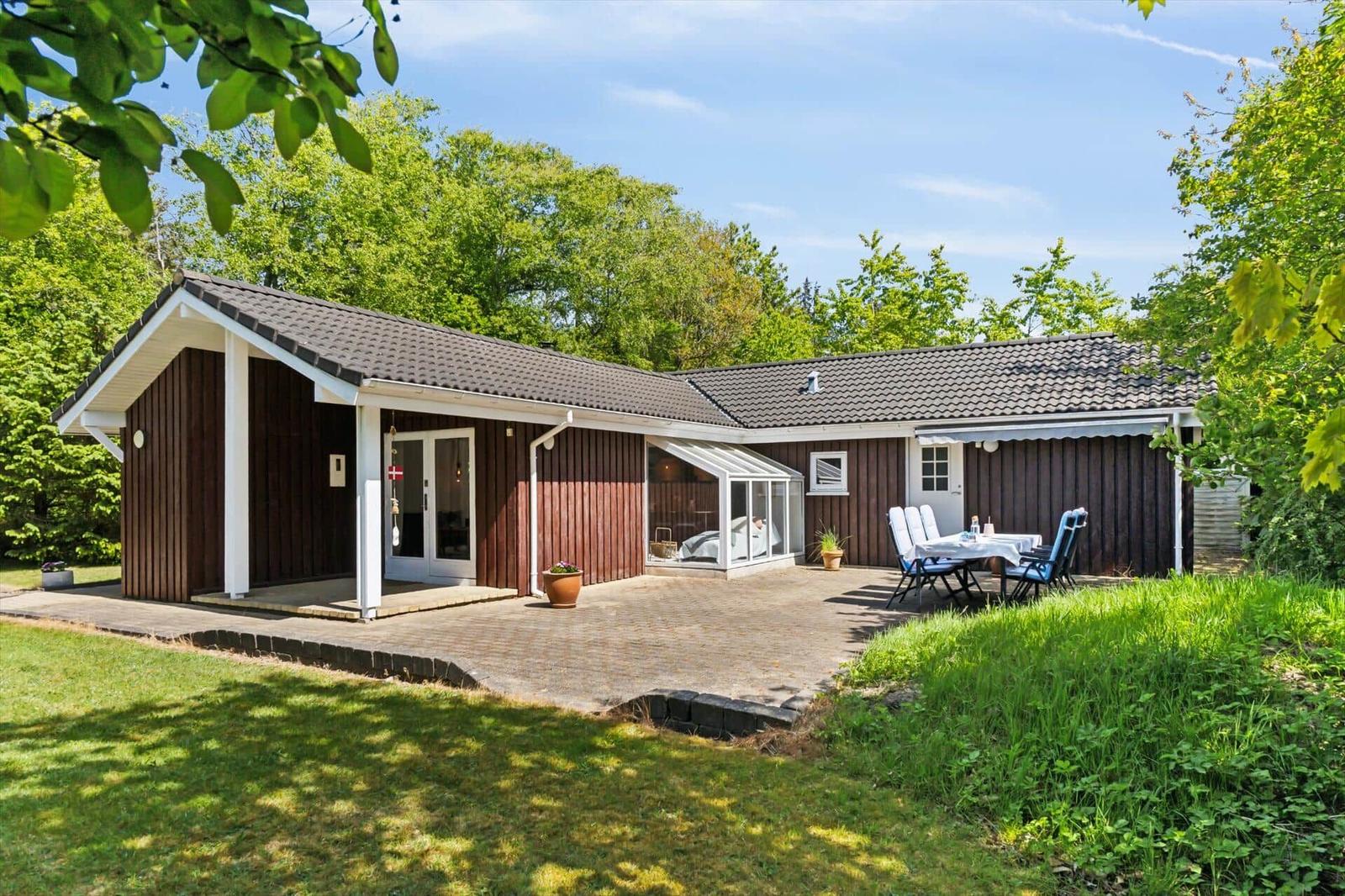 Cottage with terrace, garden and seating. Wooden walls and roof tiles.