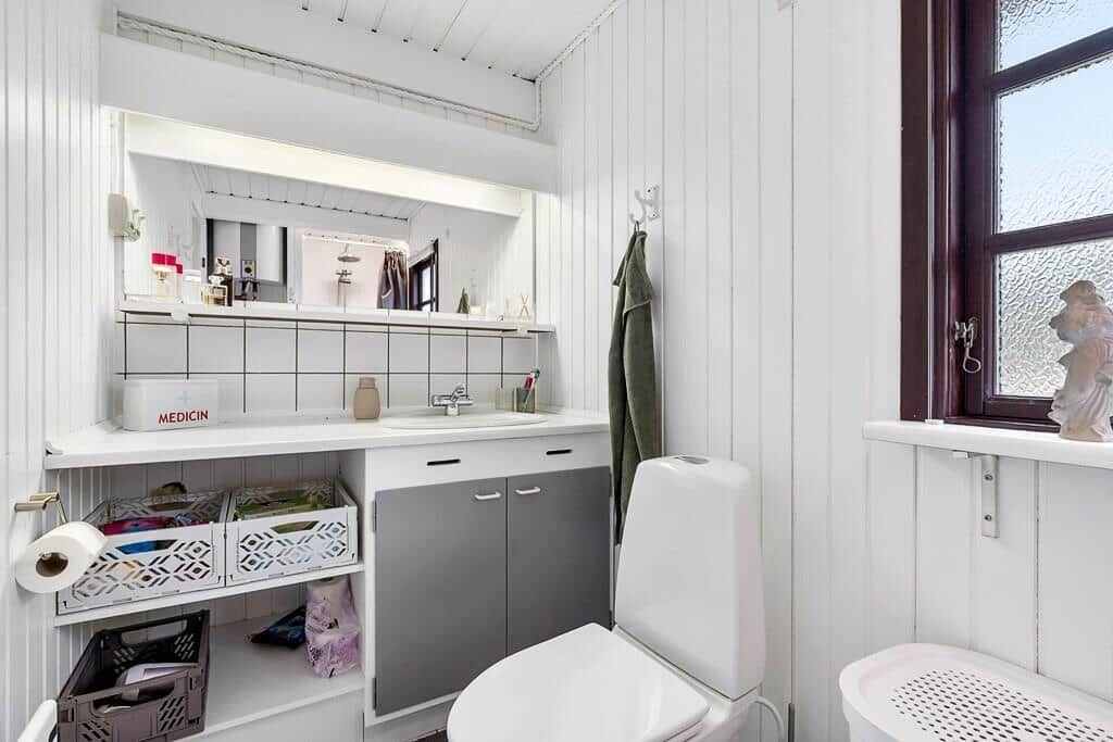 Badezimmer mit Waschbecken, Spiegel, Toilette und Fenster