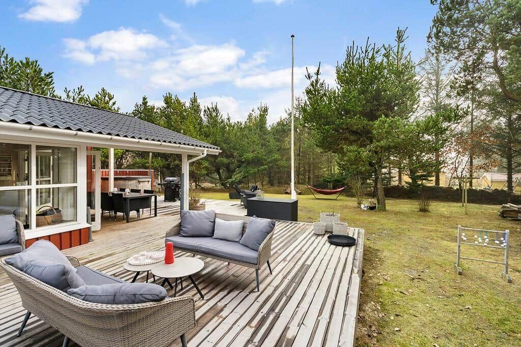 Terrasse mit Sitzgelegenheiten, Grill und Hängematten im Grünen.