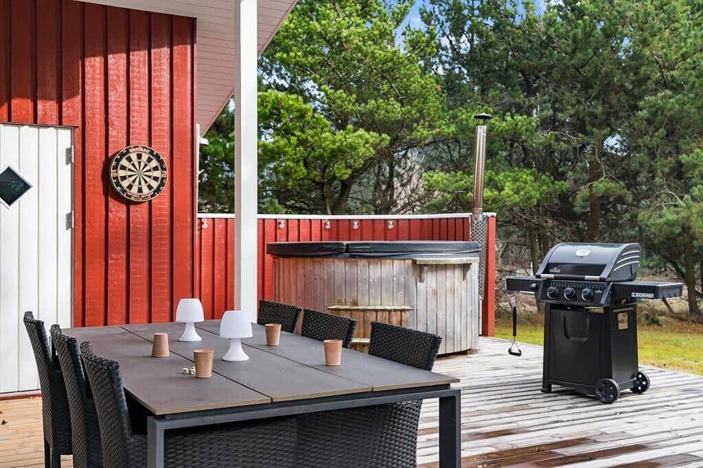 Terrasse mit Esstisch, Grill und Whirlpool. Dartboard an der Wand.