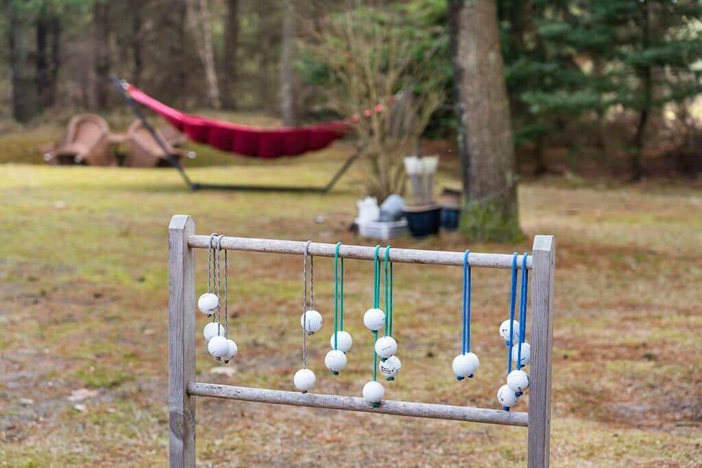 Golfbälle an einem Holzgestell im Freien. Im Hintergrund eine rote Hängematte.