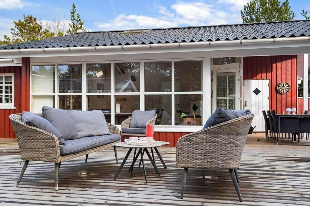 Terrasse mit Sitzgruppe und Tisch vor rotem Haus mit Fensterfront