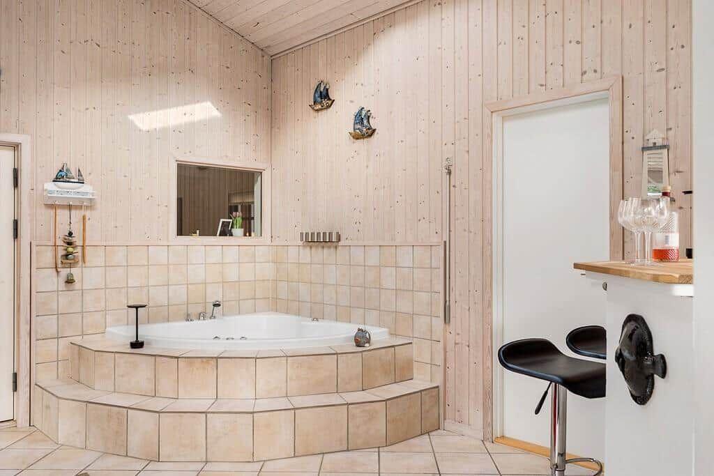 Bad mit Whirlpool, Holzwand und Bar mit Stühlen