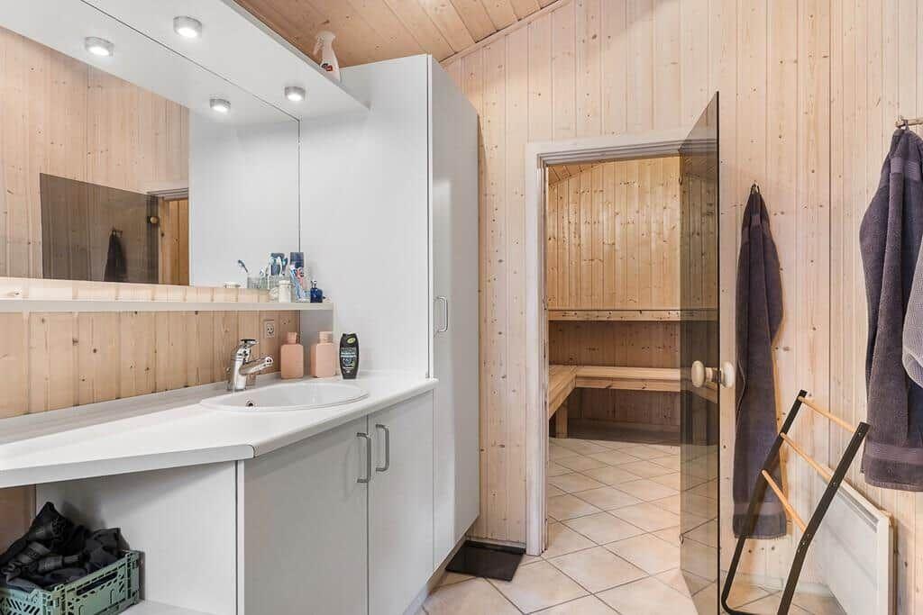Badezimmer mit Dusche und Sauna. Weiße Waschbecken und Holzwände.