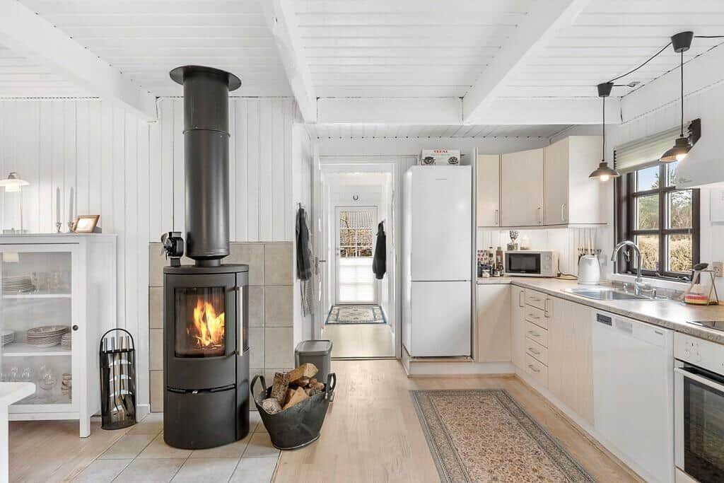 Küche mit Holzfußboden, Kaminofen und Küchenschränken
