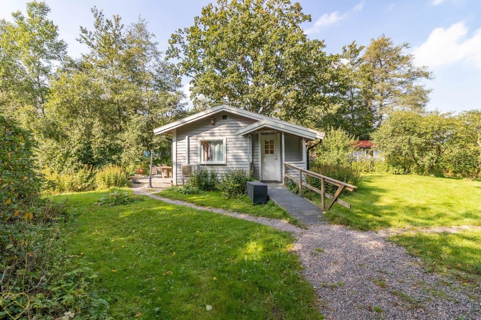 Ein kleines Haus mit weißen Wänden, einem Eingang und einem Gartenweg.