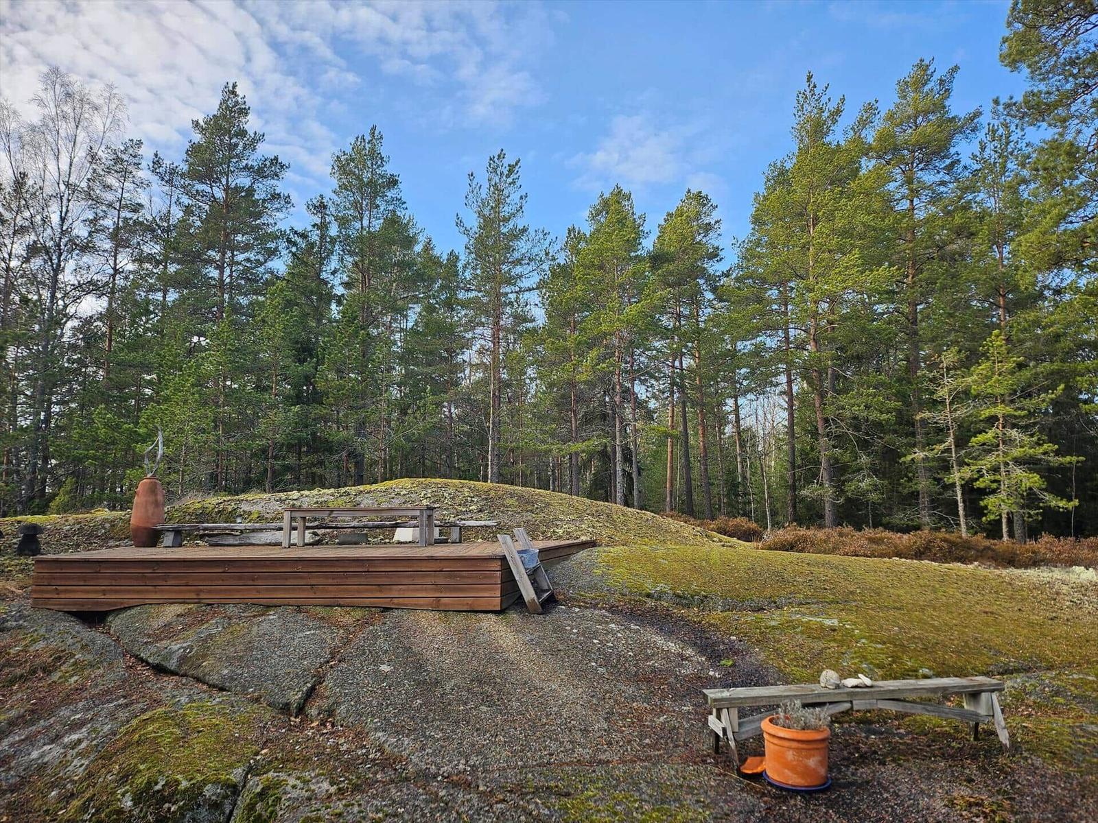 Holzterrasse auf Stein mit Sitzgelegenheiten im Wald