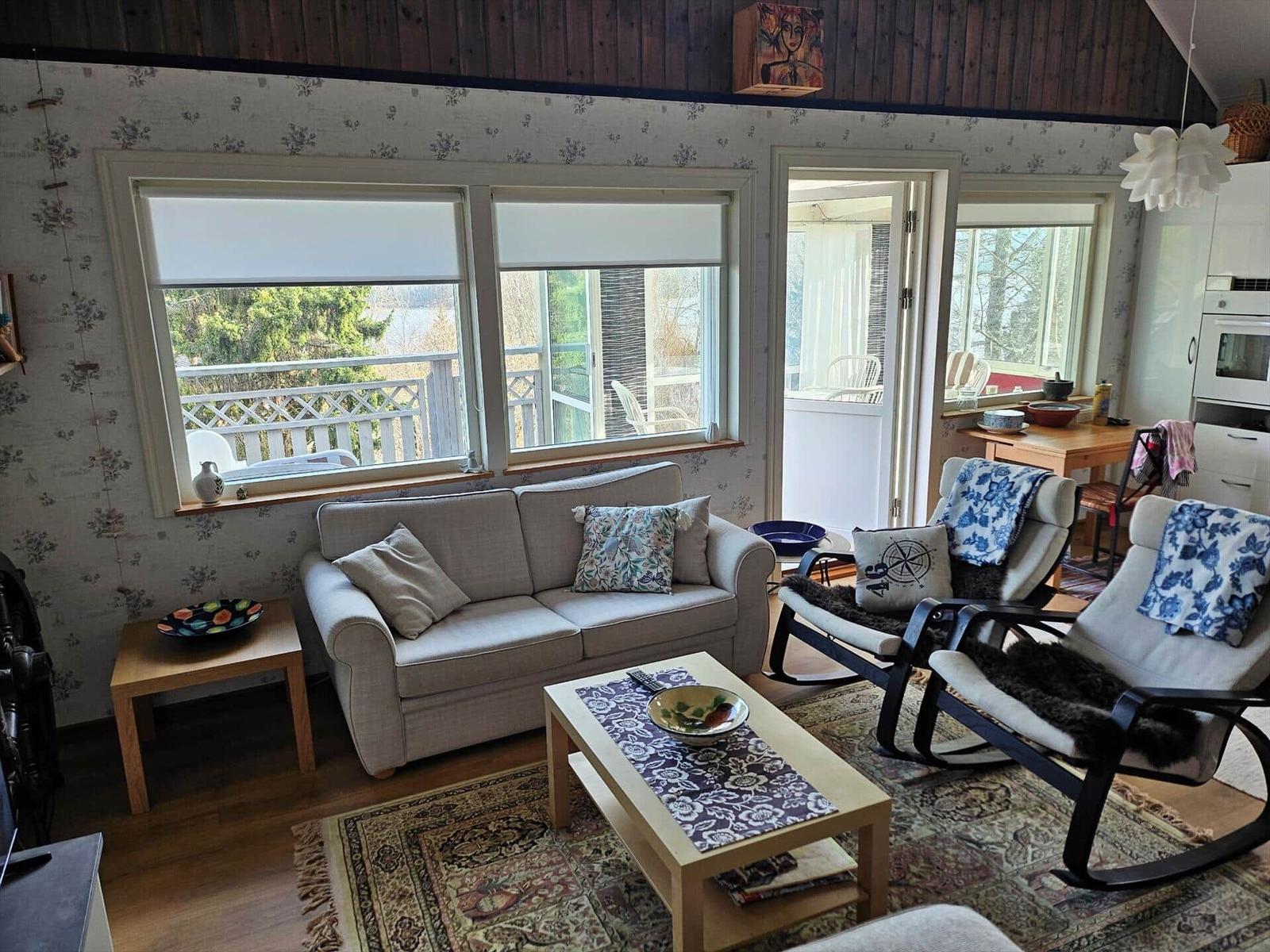 Wohnzimmer mit Sofa, zwei Sesseln und Blick auf Balkon