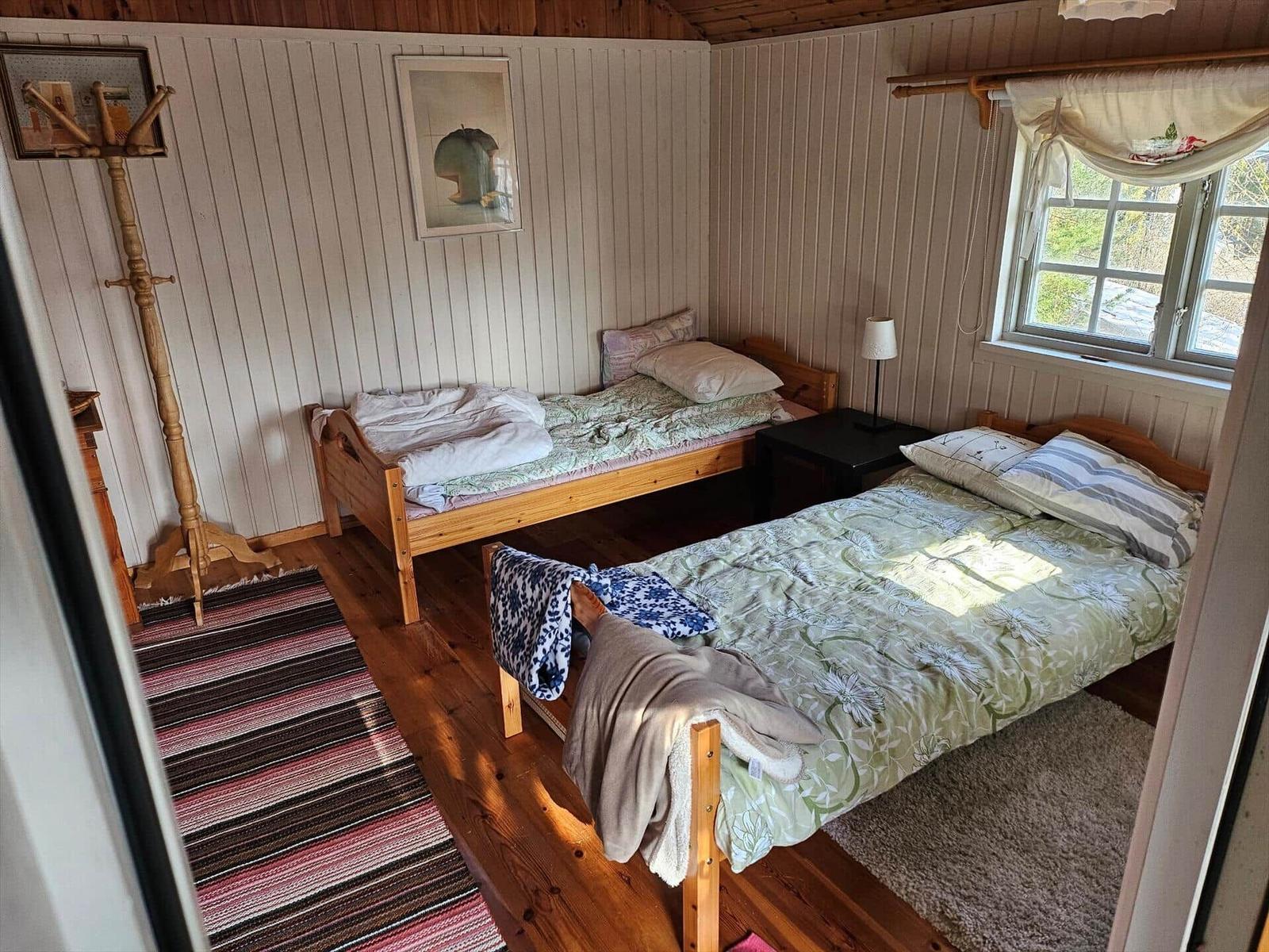 Zwei Betten, Fenster, Holzboden und Wandverkleidung in einem Schlafzimmer.