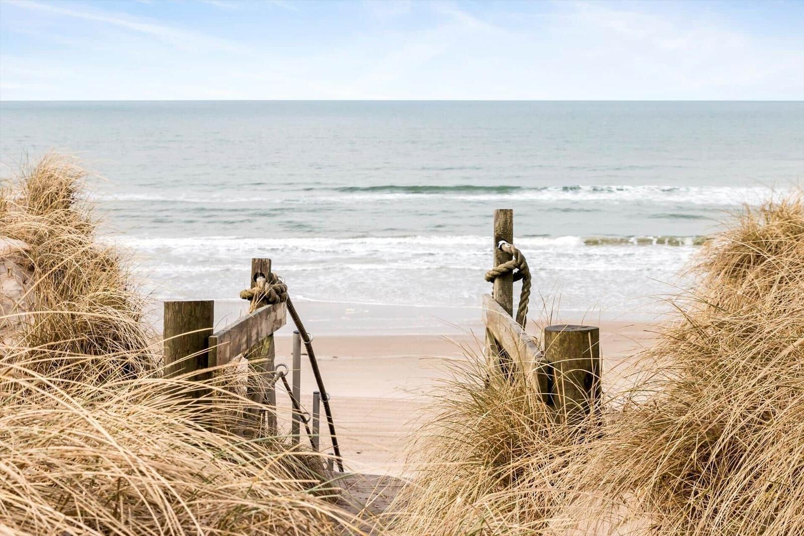 Holzsteg führt vom Dünenhügel direkt zum Strand und zum Meer.