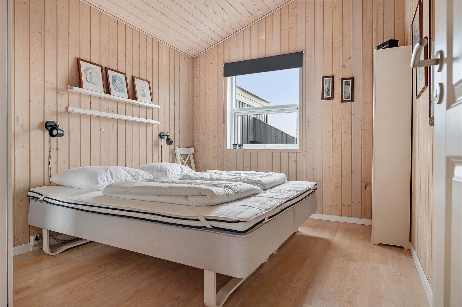 Bedroom with wooden walls, bed, and window