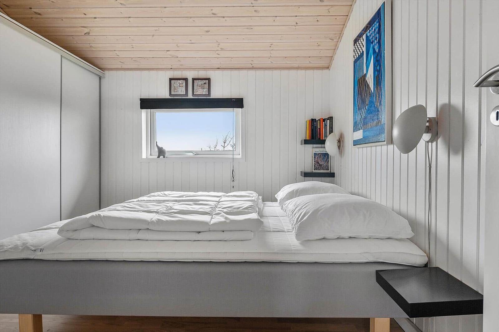 Bedroom with bed, window, and wall shelves.